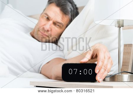 Mature Man Turning Off Clock