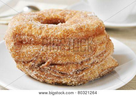 some croissant-doughnut pastries sprinkled with sugar and a cup of coffee