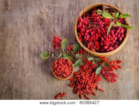 Barberry And Dry Goji Berries In Two Bowls On Wooden Background