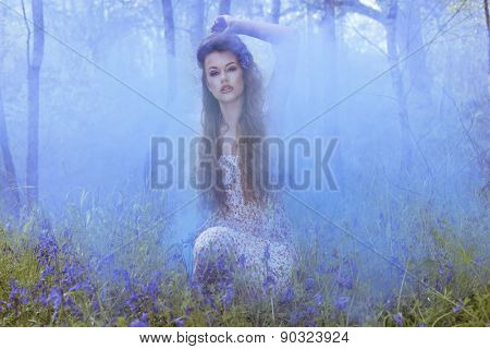 Artistic portrait of a girl surrounded by smoke in blue