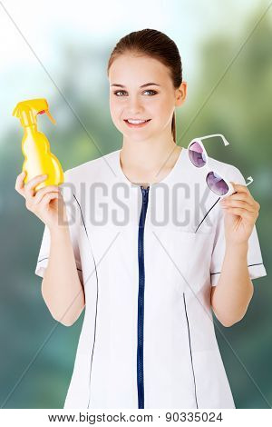 Young female doctor showing sunscreen and sun glasses.
