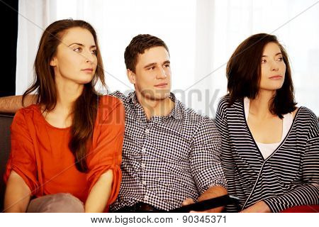 Sisters and brother relaxing at home on the sofa.