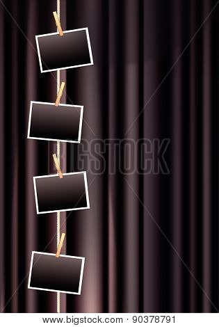 Blank photo frames hanging from a clothes line on a black curtain