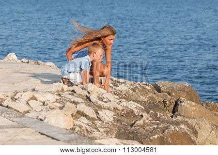 Happy Cute Big Sister And Little Brother Sitting On Beach