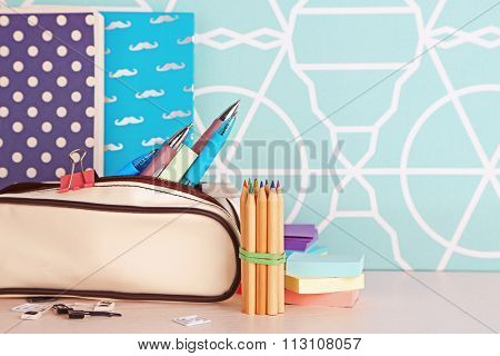 Pencil case with various stationery on wooden table, close up