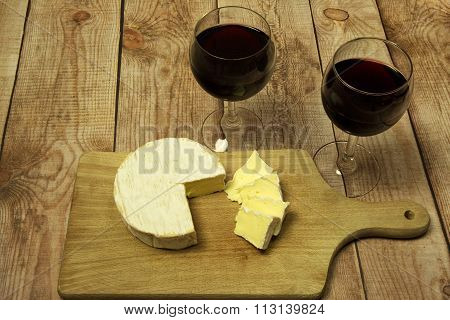 Two Wine Glasses With Red Wine,bottle Of Wine And Cheese On Wood