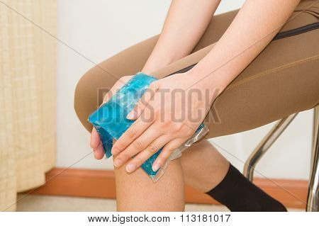 Woman Applying Cold Pack On Swollen Hurting Knee After Sport Injury