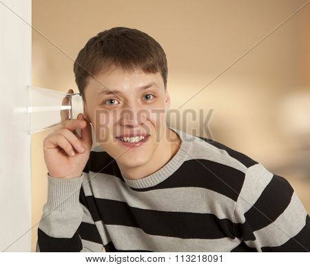 Cuckold concept. Man spying by listening through wall with glass