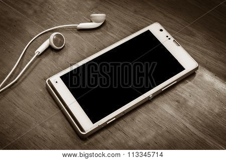 beautiful earplugs and smartphone on wood surface with color filters vintage
