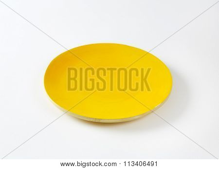 Rimless round plate with yellow glaze