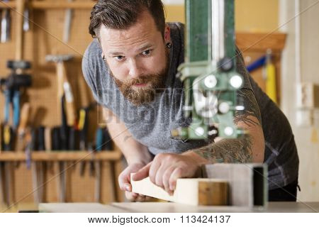 Craftsman using bandsaw for splitting wood plank in workshop