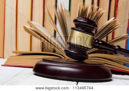 Law concept - Open law book with a wooden judges gavel on table