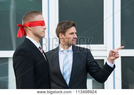 Businessman Assisting Blindfolded Partner