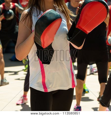 Girl In White Sportswear Doing Fitness With Punching Mitts In Outdoor Class At Gym