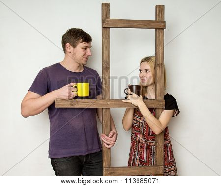 A Couple With Cups Is Resting During The Repair Near A Wooden Construction