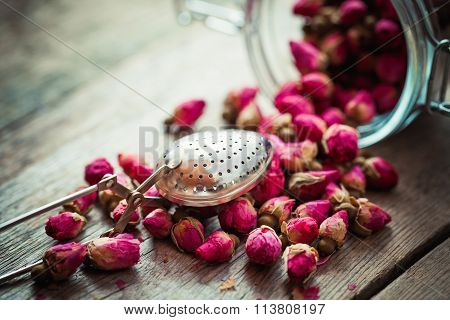 Rose Buds, Tea Strainer And Glass Jar On Rustic Wooden Table. Retro Styled. Selective Focus.