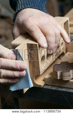 Man sandpaper grinds wood product in one studio