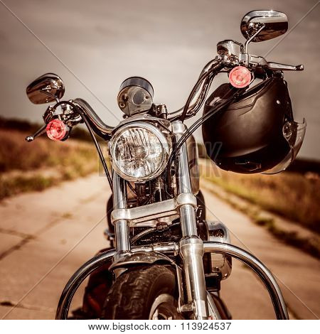 Motorcycle on the road with a helmet on the handlebars.
