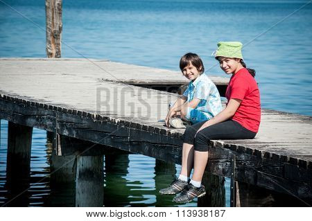 Girld and boy on lake dock in Italy