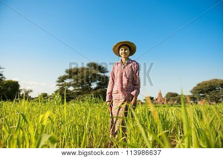 Portrait of a young Asian Myanmar farmer with thanaka powdered face standing in the farm field.