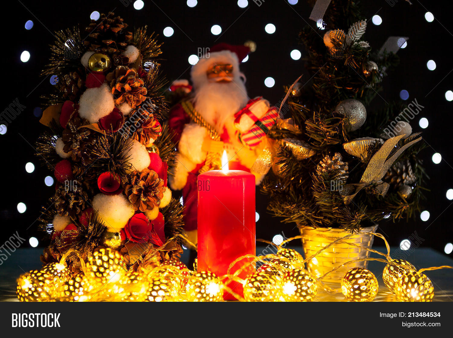Two Mini Christmas Trees And A Santa Claus Figurine On Black Background With Bokeh Lights On Two Mini Christmas Trees And A Santa Claus Figurine On Black Background With Bokeh Lights On