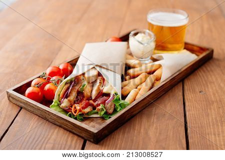 Shawarma on a tray. Fast food. Eastern food. Street food. Shaverma, shawarma, shaurma, pita gyros. Shawarma lying on pita bread and decorated with tomatoes, bread sticks, sauce and beer.