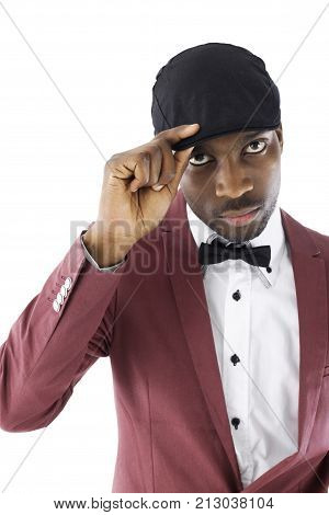 African male with his hand on his hat is dressed in a vintage suit standing with a blank expression