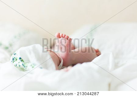 Baby feets, heels, hands in white bed