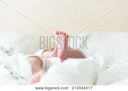 Baby feets, heels, hands in white bed