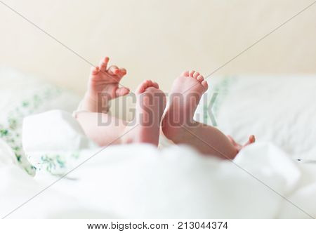 Baby feets, heels, hands in white bed