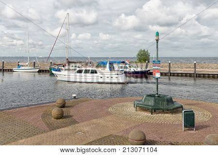 URK, THE NETHERLANDS - JUNE 18, 2016: Harbor of historic fishing village Urk with modern yacht sailing to the sea.