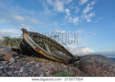 Old boat shore evening light sunset clouds and architecture concept in the Baltic Sea. Mohni small island in Estonia Europe.