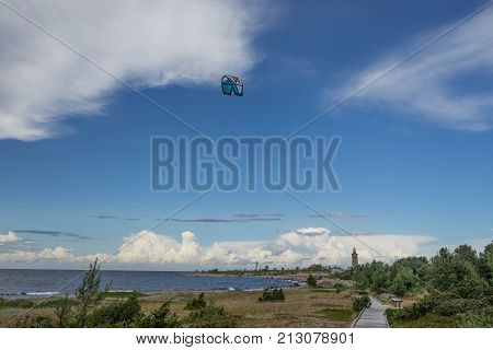 A kite surfer rides on the sea. Kites in the sky. Kite Boarding extreme sport on Mohni small island in Estonia Europe.