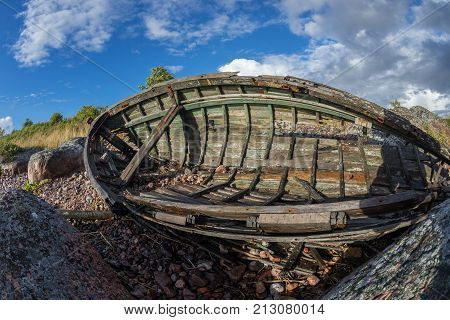 Old boat shore evening light sunset clouds and architecture concept in the Baltic Sea. Mohni small island in Estonia Europe.