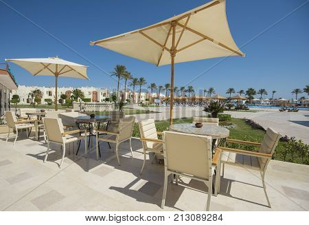 Outdoor patio terrace area with table set up and parasol umbrellas at tropical luxury hotel resort