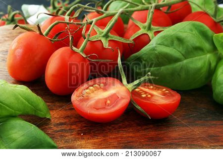 Cherry tomatoes with basil and dish towl on cutting board.