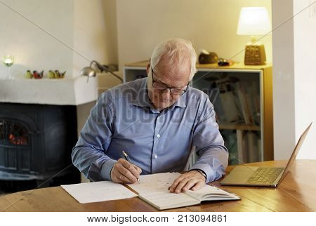 Working businessman sitting at a desk with a computer in a cozy home interiour making calculations