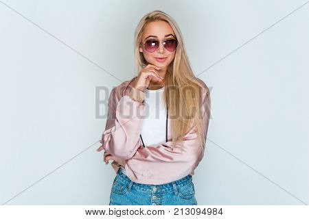 Hmmm that is interesting. Beautiful young woman with blond hair looking at camera with smile while standing against grey background