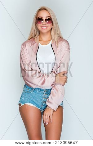 Cheerful and beautiful. Beautiful young woman with blond hair looking at camera with smile
while standing against grey background