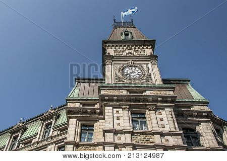 Classic clocktower building in Quebec City Canada with flag of quebec on a sunny day blue sky