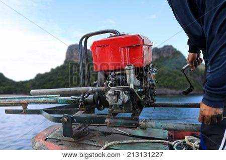 Men are repairing engines adapted for long-tail boats. Maintenance the chain gear and equipment for modified old diesel engine and spare parts in Thailand.