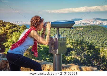 ISTANBUL TURKEY: Beautiful girl is looking through the telescope at Asian Side of Istanbul from Buyukada Island with Marmara Sea landscape on October 9 2017
