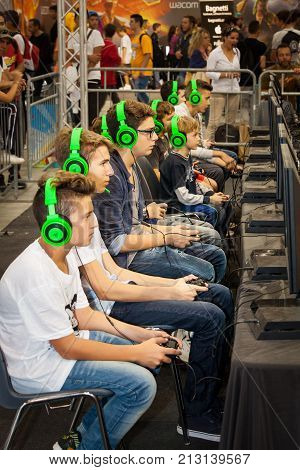 ROME, ITALY. October 03, 2015: Boys tournament players and gaming consoles. Row of young boys playing with a console. Wearing headphones. Romics 2015 in Rome, Italy. Festival of comics and gaming.