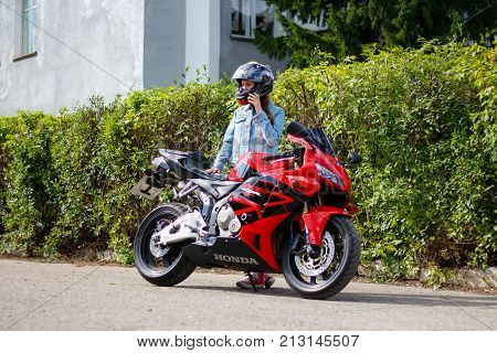 Krasnoyarsk, Russia - August 09, 2017: A Girl Motorcyclist Wearing A Helmet And Red Sport Bike Honda