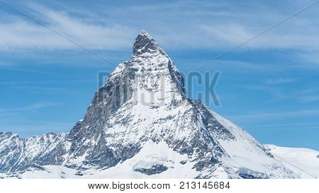 Iconic view of Snowy Matterhorn peak with blue sky and some clouds in background Switzerland