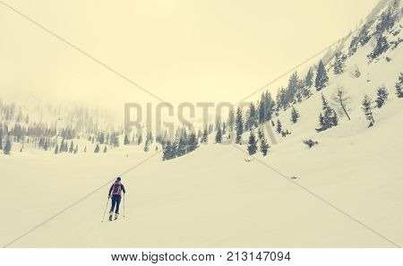 Lonely back country skier walking through a misty valley. Exploring winter fairytale.