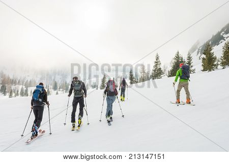 Group of back country skiers walking through a misty valley. Exploring winter fairytale.