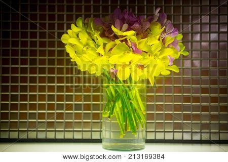 Yellow mokara orchid bouquet in glass pot