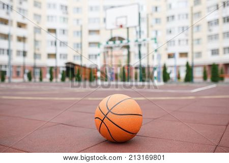 Basketball, bright, new ball lies on the red, rubber coating of the open stadium. Autumn. The concept of sport.