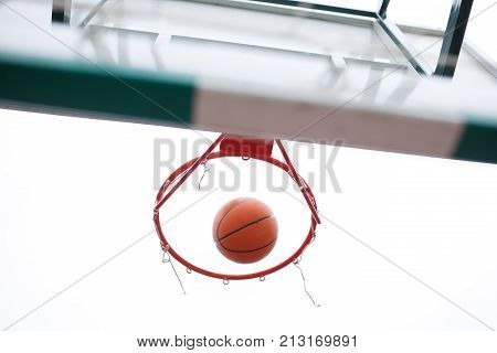 Basketball, bright, new ball flies into the ring in an open stadium. View from the bottom. The concept of sport.